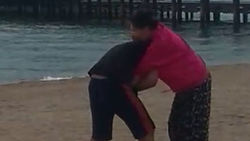 Муж и жена борются на пляже. Видео