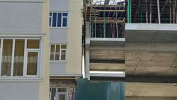 В городе Ош новый многоэтажный дом строится впритык к другому дому. Фото