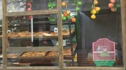 На витрине фаст-фуда на Пишпеке рядом с едой стоит клетка с птицами. Фото