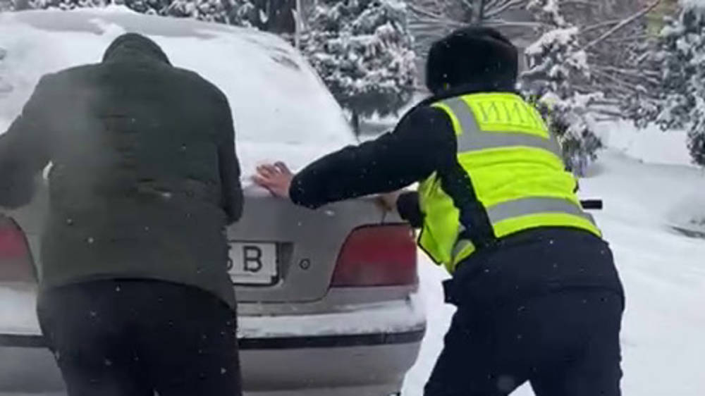 В Оше патрульный помогает толкнуть застрявший в снегу BMW. Видео
