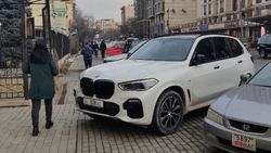 BMW X5 припаркован на тротуаре. Фото