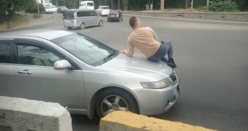 В Бишкеке мужчина едет на капоте машины. Видео