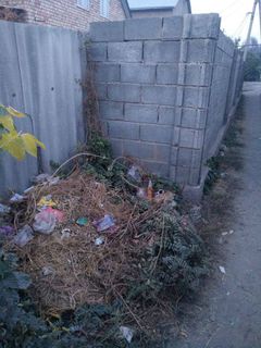 В селе Маевка под забором дома сваливают мусор